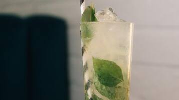 A glass with a striped straw, containing ice and mint leaves, on a marble surface.