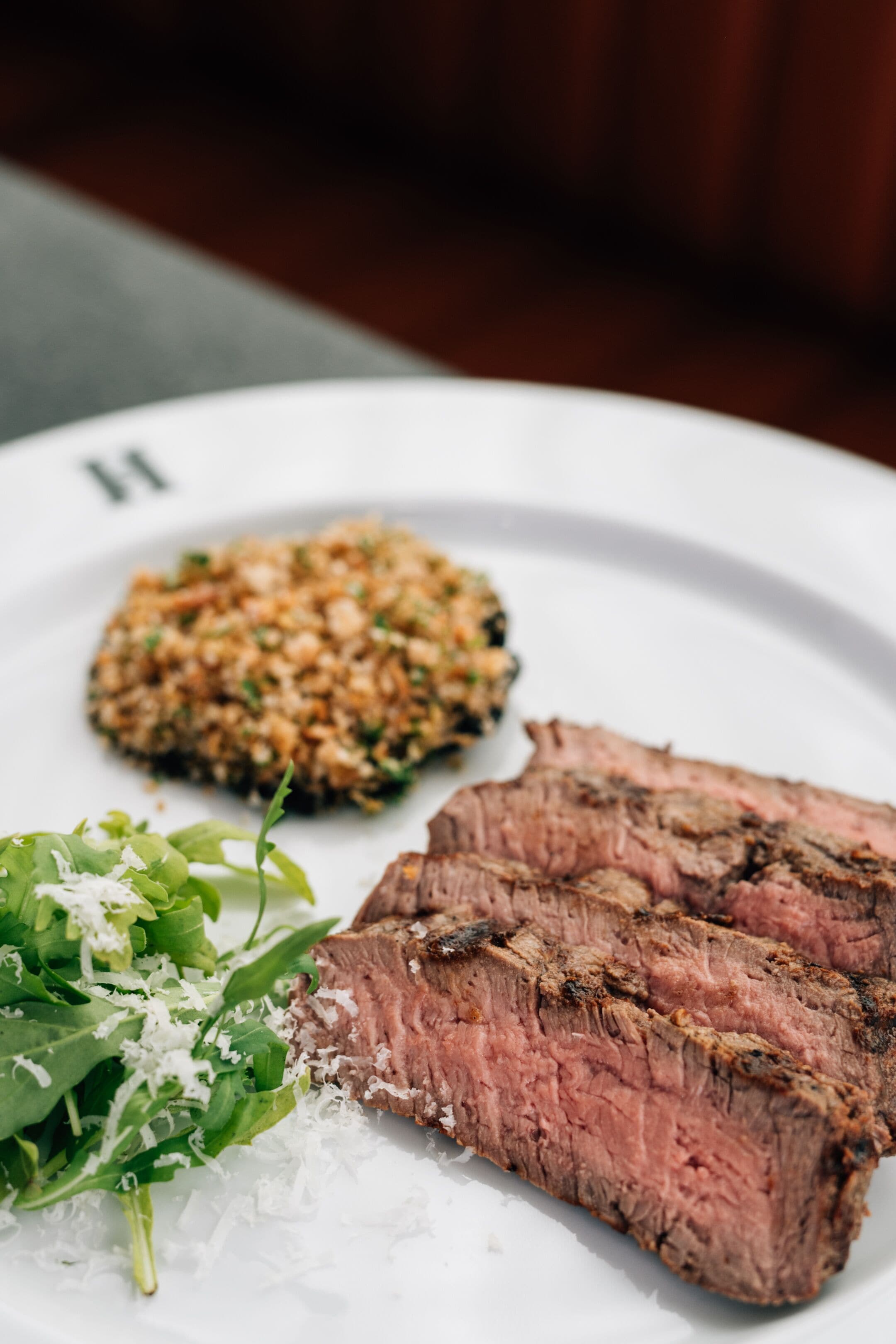 Um prato com uma fatia de bife, acompanhado de legumes e um guarnição à base de grãos.
