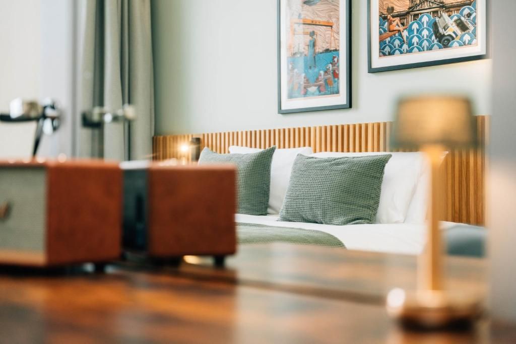 Una habitación de hotel con cama, cabecero de madera y un cuadro en la pared.