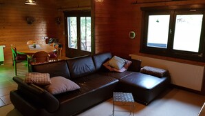 Una habitación acogedora con un sofá de cuero, una mesita auxiliar y una zona de comedor con mesa y sillas.