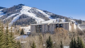 A multi-story hotel with a modern design, situated in a mountainous area with a ski lift in the background. - Ridgecrest 202 2 Bedroom Condo by RedAwning (Steamboat Springs)