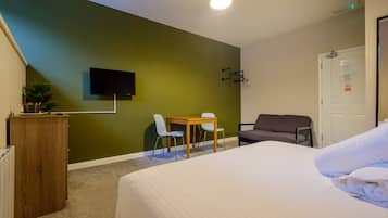 Ett hotellrum med en säng, ett skrivbord, två stolar, en tv och en soffa.