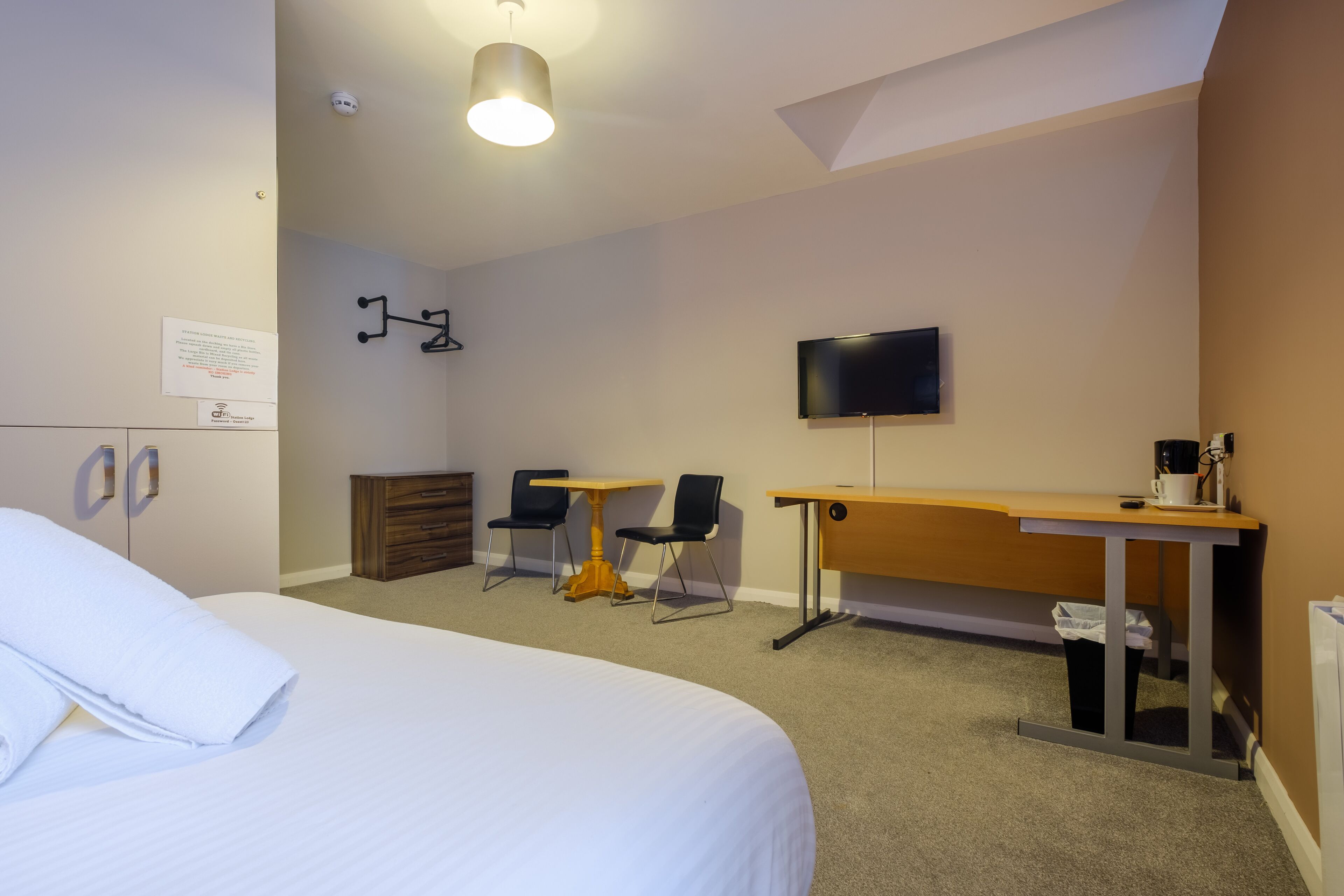 A hotel room with a bed, a desk, a chair, a television, and a small table.
