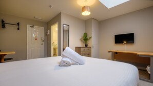 A hotel room with a large bed, a desk, a television, and a bathroom visible through an open door. - Station Lodge (Windermere)