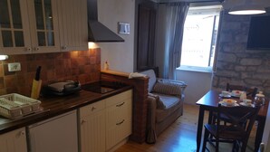 Eine gemütliche Küche mit Essbereich, mit Holzboden, Kamin aus Ziegeln und Steinwand.