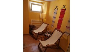 Ein Zimmer mit zwei Holz-Loungestühlen, einem kleinen Tisch, einem Fenster und einer Wandlampe.