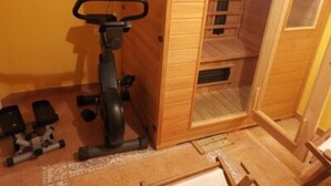 Ein kompakter Raum mit einer Holzvertäfelung, einem kleinen Heimtrainer und einem Hantelpaar.