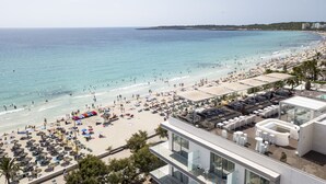 Um resort à beira-mar com área de piscina, espreguiçadeiras e guarda-sóis.