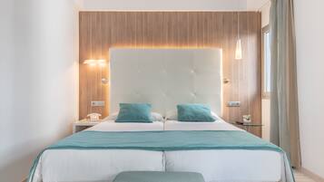 A modern bedroom with a large bed, two bedside tables, a bedside lamp, and a window with curtains.