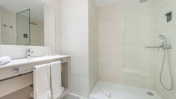 Un baño moderno con ducha envuelta en vidrio, tocador blanco con espejo y bañera.