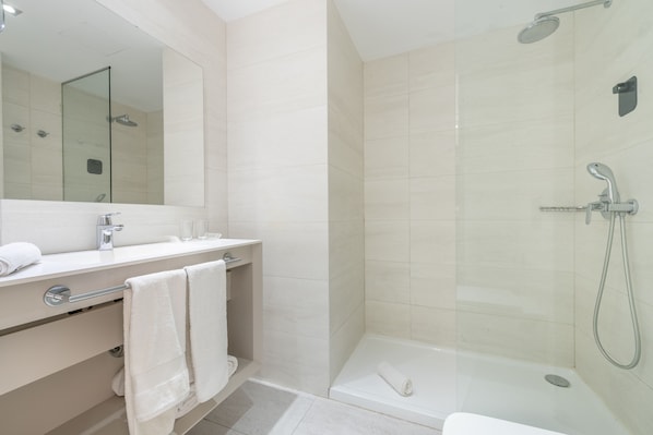 A modern bathroom with a glass-enclosed shower, a white vanity with a mirror, and a bathtub. - Kyrat Amarac (Son Servera)