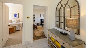 Ein Hotelzimmer mit einem Bett, einem Schminktisch, einem Spiegel und einer Tür zu einem anderen Raum.