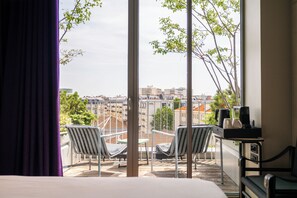 A hotel room with a large window, two chairs, a small table with a coffee maker, and a bed. - mk2 Hotel Paradiso Nation (Paris)