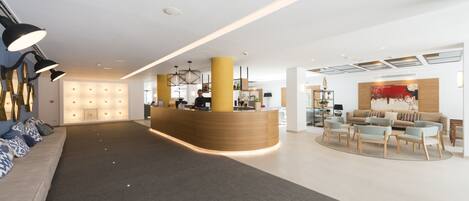 A spacious lobby with a reception desk, seating area, and a modern chandelier.