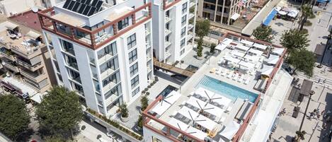 A high-rise building with multiple balconies, a rooftop pool, and solar panels.