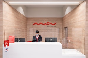 Een receptie met een receptioniste, een digitaal scherm en een bord met daarop Smart Moov Hotel.