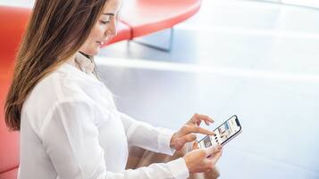 Une personne assise sur une chaise rouge et utilisant un téléphone intelligent.