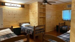 A cabin-style room with three wooden beds, a ceiling fan, and a window with curtains. - Club Getaway Valley View 1 (Kent)