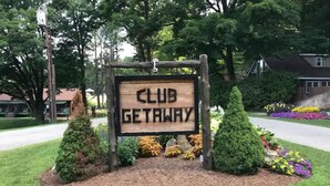 A wooden sign with the text "CLUB GETAWAY" surrounded by landscaped bushes and flowers. - Club Getaway Mountain View 3 (Kent)