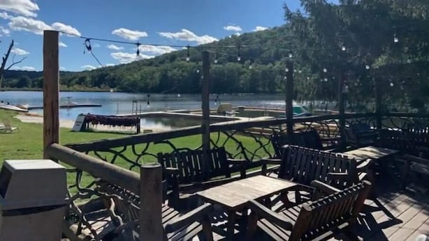 A deck with outdoor seating overlooking a lake, surrounded by greenery and a clear sky. - Club Getaway Mountain View 3 (Kent)
