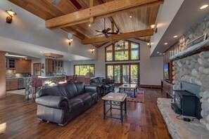 A spacious living area with a leather sofa, a coffee table, and a stone fireplace.