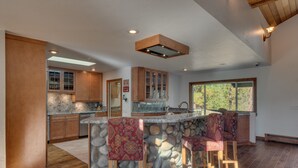 A kitchen with a stone island, wooden cabinets, and a large window. - 5 Bedroom close to Town, hot tub, BBQ(SL437) (Stateline)
