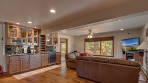 A spacious kitchen with wooden cabinets and a large island, a brown leather sofa, and a television on the wall. - 5 Bedroom close to Town, hot tub, BBQ(SL437) (Stateline)