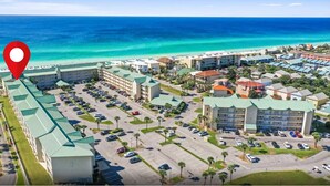 Une vue aérienne d’un complexe hôtelier comprenant plusieurs bâtiments, un parking et une plage en arrière-plan.