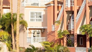 Un hotel de fachada rosa, con balcones y una escultura de ballena azul en el jardín.