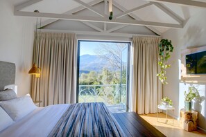 Ein Schlafzimmer mit einem großen Bett, Bergblick und einem Balkon mit Vorhängen.