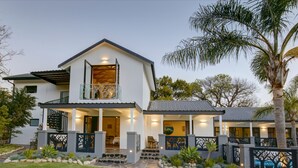 Une maison moderne à deux étages, dotée d’un balcon, d’un chemin en pierre et d’un jardin bien entretenu.
