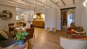 Une pièce spacieuse dotée d’un plancher en bois, d’un coin repas avec des chaises et une table, d’un canapé et d’un grand miroir agrémenté de cadres décoratifs.