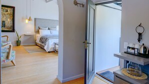 Une chambre moderne avec un lit, un bureau et une chaise. Une porte donne accès à une autre pièce.