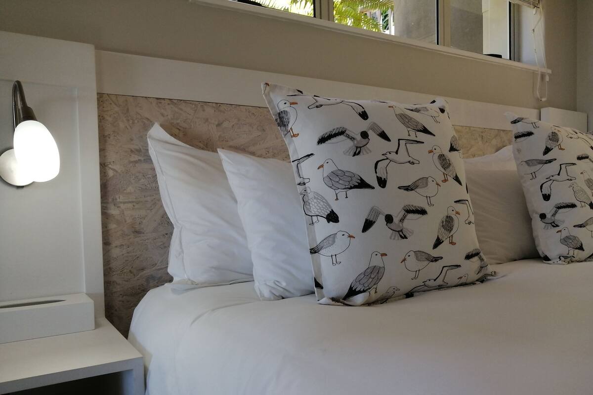 A bed with white bedding and patterned pillows, a bedside lamp, and a marble headboard.