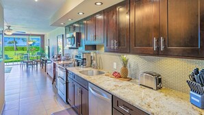 A modern kitchen with dark wooden cabinets, granite countertops, and stainless steel appliances.