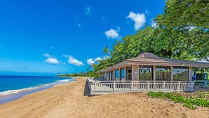 A beach with a covered pavilion, sandy beach, and ocean view.