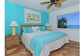 Relax in this serene bedroom with a large bed, two nightstands, and a ceiling fan. Enjoy the view from the large window.