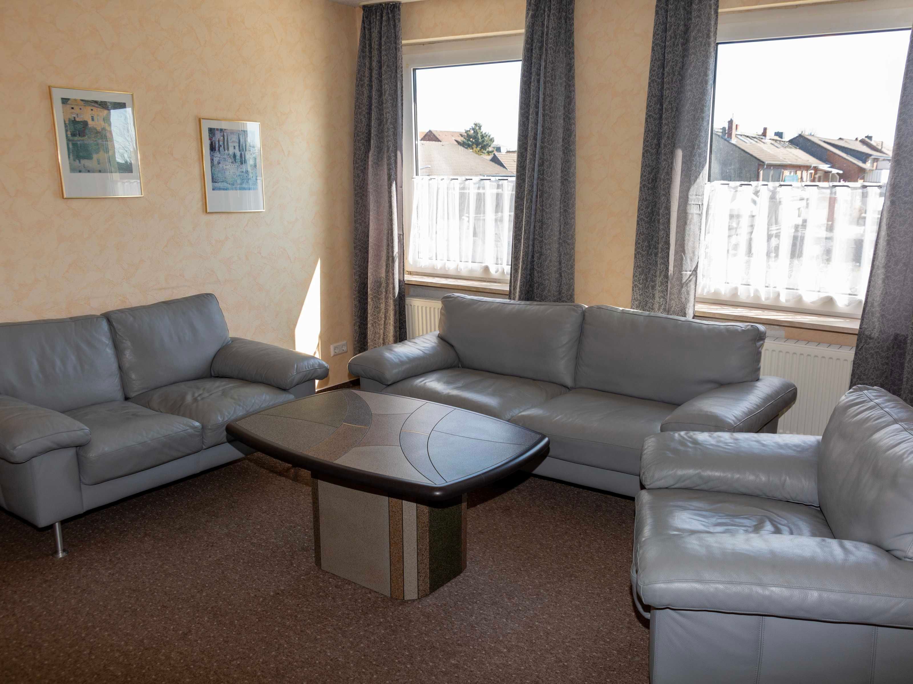 A living room with a grey sofa set, a coffee table, and two framed pictures on the wall.