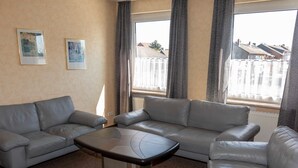 A living room with a grey sofa set, a coffee table, and two framed pictures on the wall.