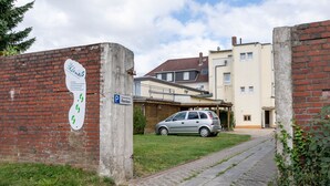 A paved pathway leading to a building with a parked car.