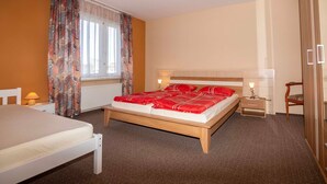 A bedroom with a bed, a bedside table, a lamp, a chair, and a wardrobe.