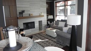 A modern living room with a fireplace, a sofa, a coffee table, and a lamp. - FAB FITZWALK Townhome FAMILY GETAWAY! Hot Tub, 2 car garage, minutes to Village (Whistler)