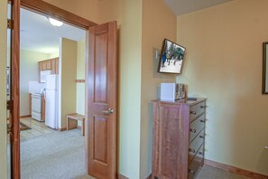 A hallway with a wooden door, a small cabinet with drawers, and a framed picture on the wall.