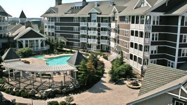 Ein Resort mit mehrstöckigen Gebäuden, einem zentralen Pool und einem Pavillon.