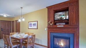 Ein Essbereich mit Kamin, Holzsesseln, einem Tisch für vier Personen und einem gerahmten Bild an der Wand.