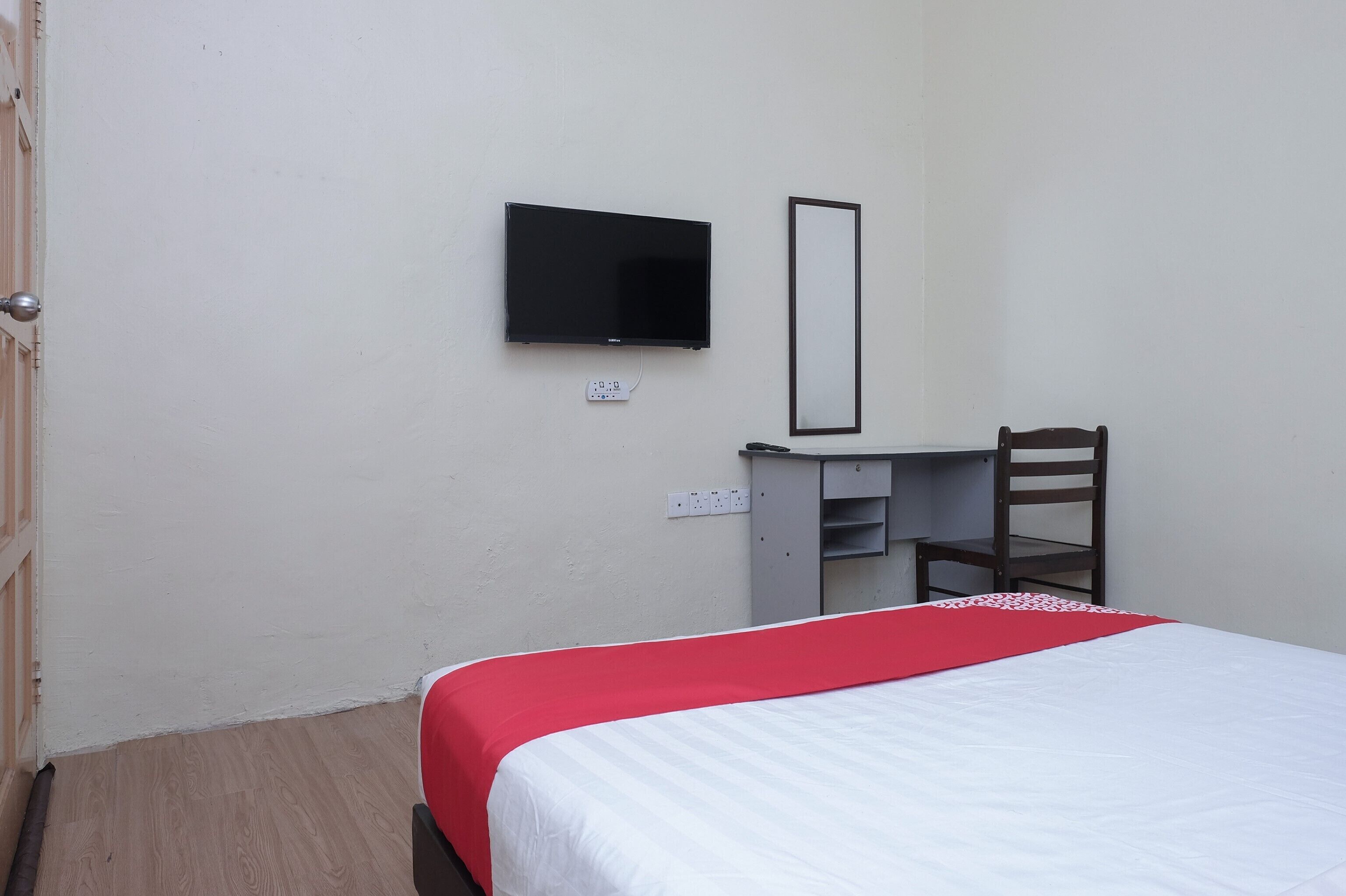 Ein Hotelzimmer mit einem Bett, einem Schreibtisch, einem Stuhl, einem Fernseher und einem Spiegel.