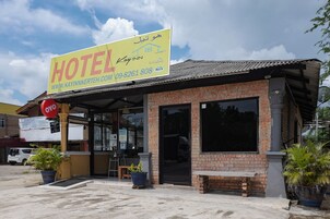 Un hotel con un letrero llamativo, fachada de ladrillo y plantas en macetas.