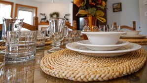 A dining table set with clear glassware, white plates, and a centerpiece of flowers. - Camp 4 24: Slope Side, Cozy 2 BR with Shuttle Service (Snowshoe)