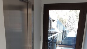 A hallway with a sliding door leading to a balcony with a metal railing. - La Esquina (San Martín de los Andes)