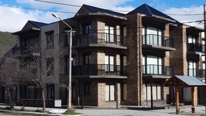 A multi-story building with a modern architectural design, featuring balconies and large windows. - La Esquina (San Martín de los Andes)